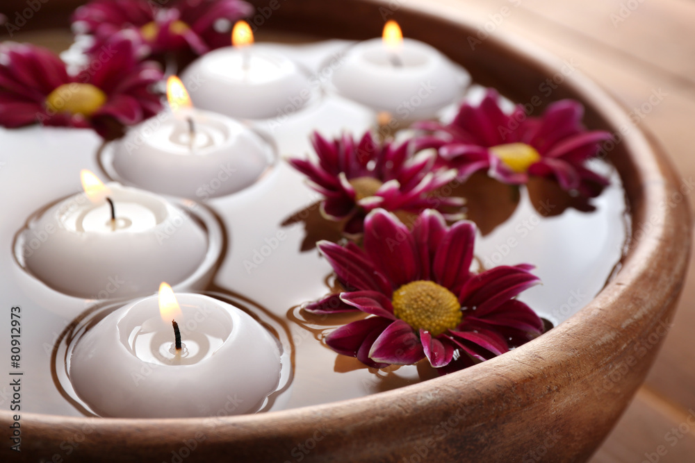 Bowl of spa water with flowers and candles, closeup Bowl of spa water with flowers and candles, closeup