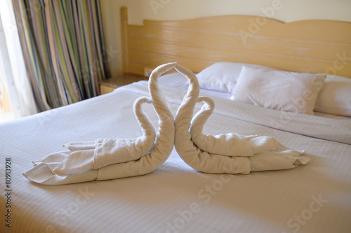 Tucked bed with swans out of towels in a hotel room