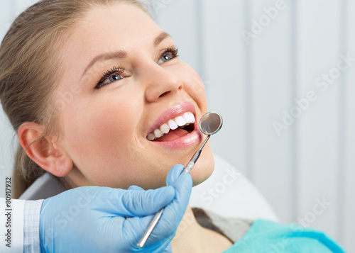 Dentist checking parient teeth holding dental mirror