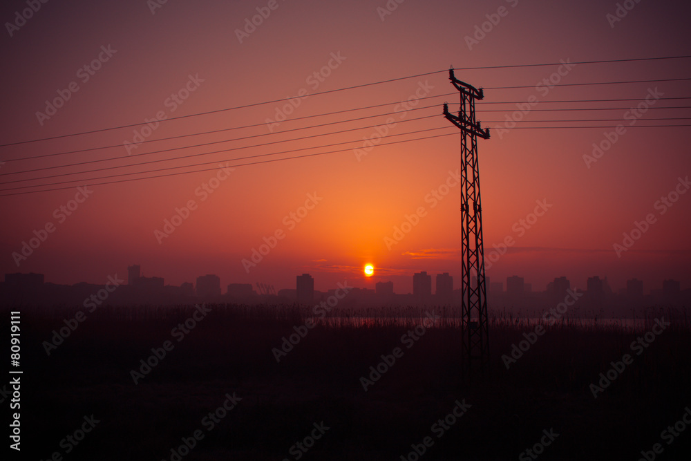 Power pole silhouettes in orange purple cloudy sunset background