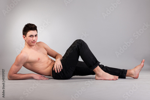 Healthy muscular young man on grey background