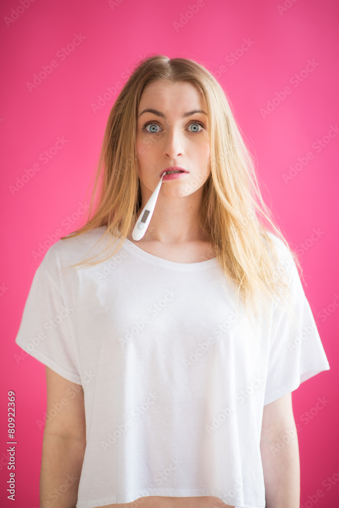 Blonde Frau mit Fieberthermometer schaut erschrocken Blonde Frau mit Fieberthermometer schaut erschrocken