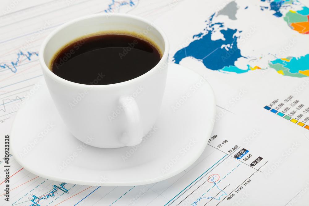 Coffee cup over world map and some market charts Coffee cup over world map and some market charts
