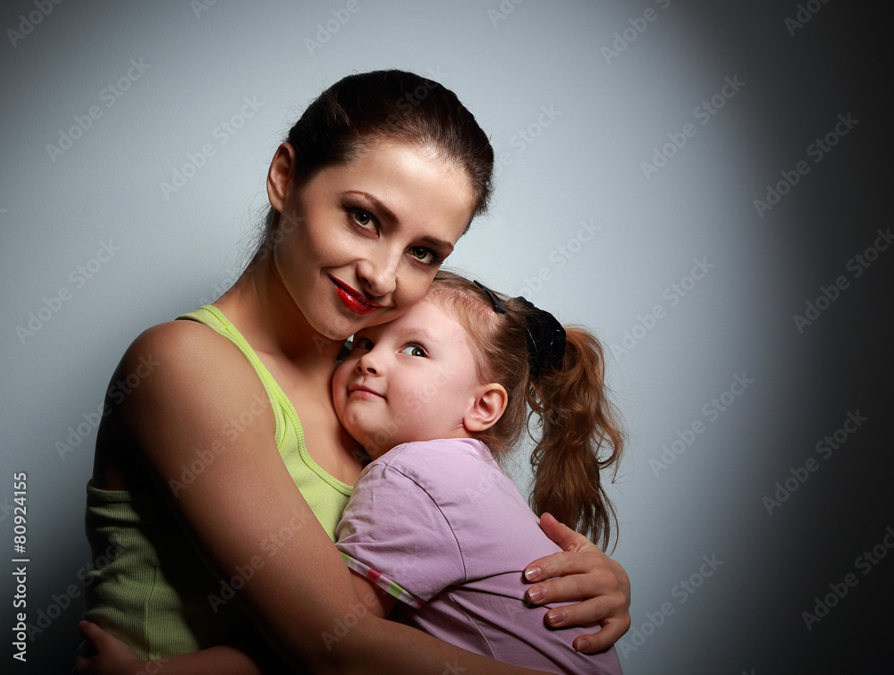 Young mother and happy daughter cuddling on dark
