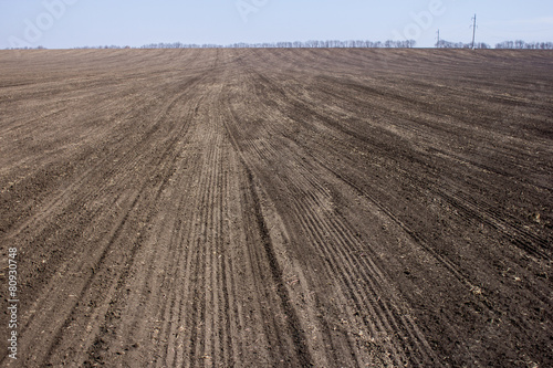 an image of black ploughed field under blue sky