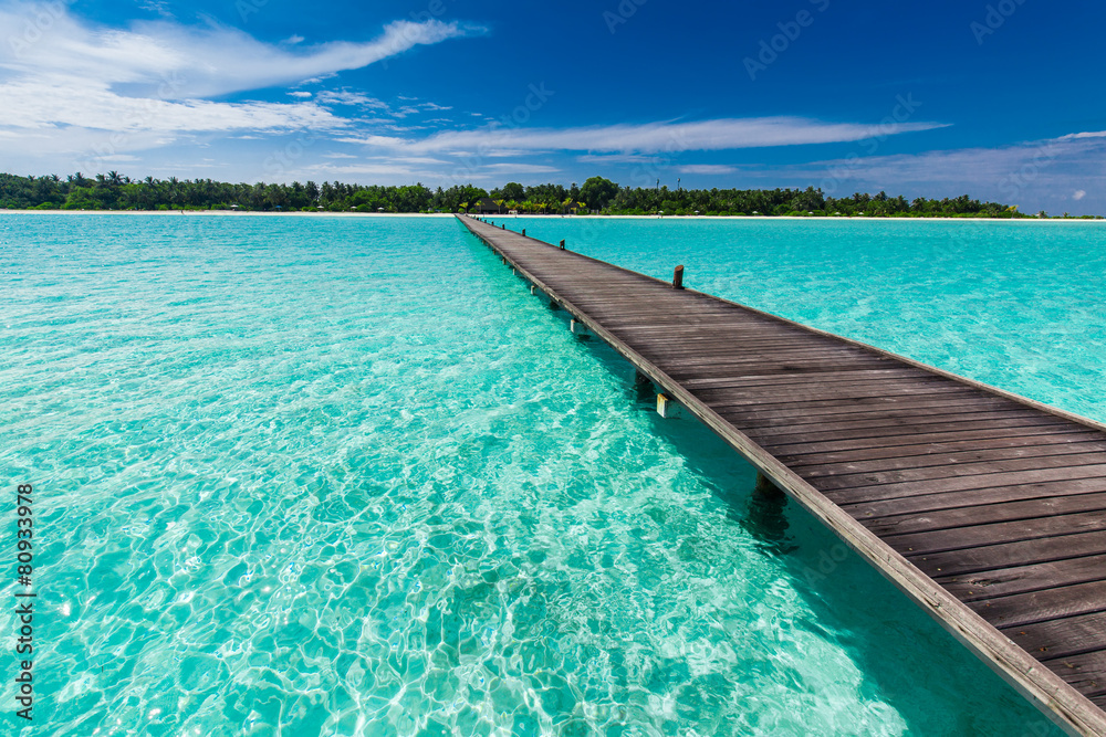 Wooden long jetty over lagoon in Maldives with amazing water