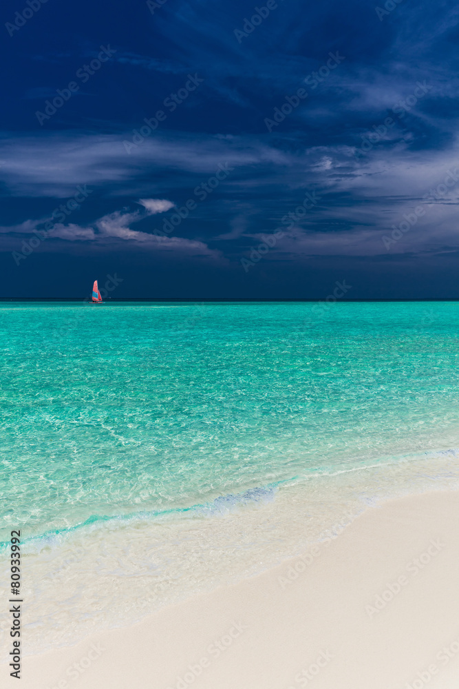 Paradise beach in Maldives with single red sail boat Paradise beach in Maldives with single red sail boat