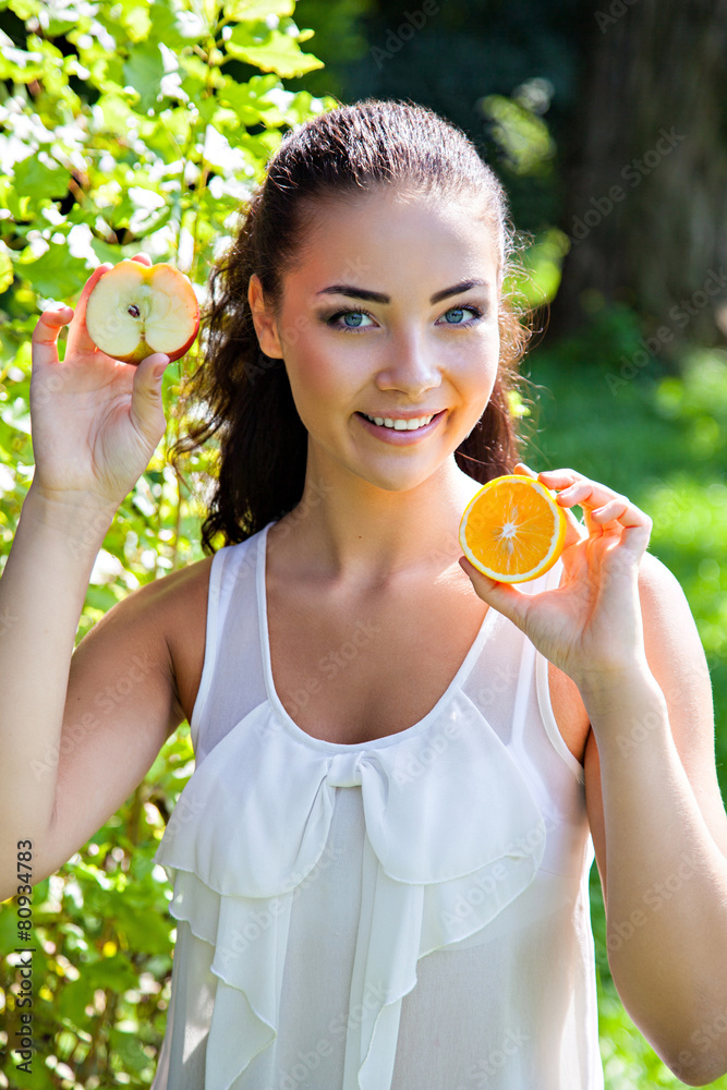 Beautiful close-up portrait of young woman with orange and apple Beautiful close-up portrait of young woman with orange and apple