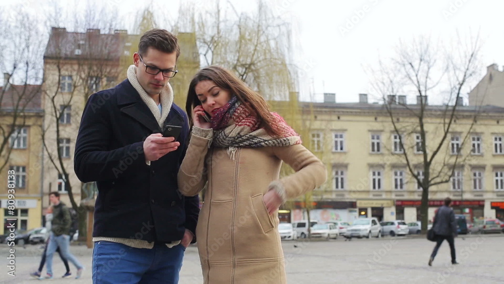 Couple standing on public square and using modern technology Couple standing on public square and using modern technology
