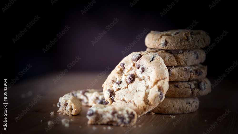 Stack of chocolate chip cookies on wooden table. Shallow DOF. Fo