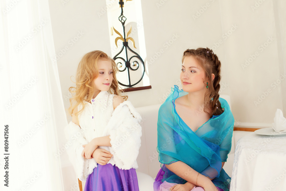 Fototapeta premium Playful well-dressed sisters looking at each other