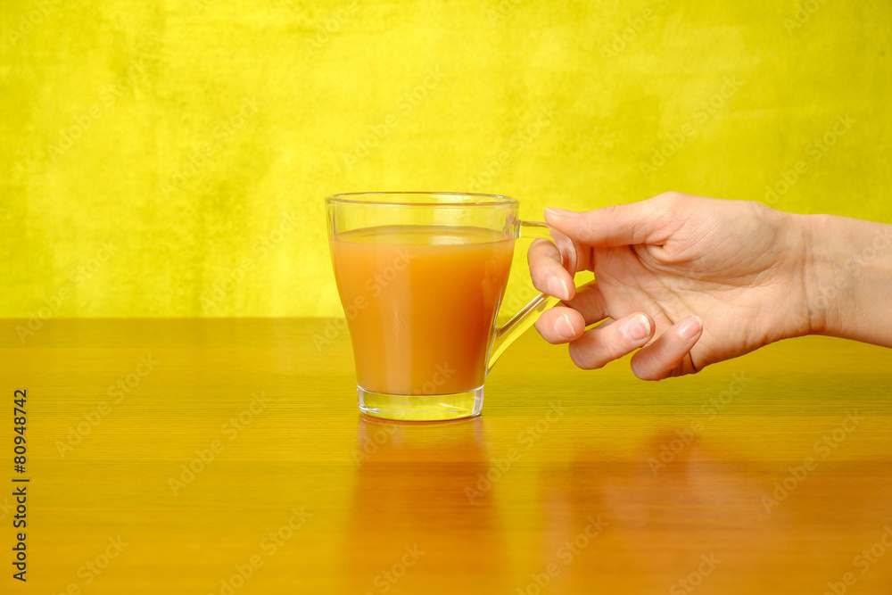 Woman's hand is holding peach juice in the glass Woman's hand is holding peach juice in the glass