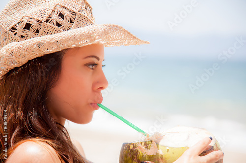 woman drinking with a staw from a coconut photo