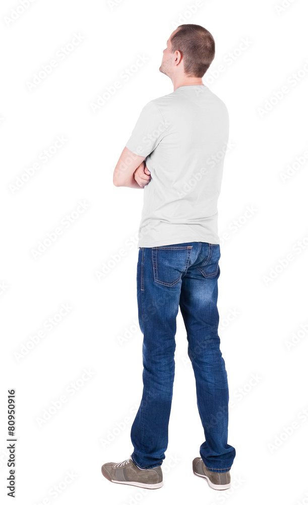 Back view of young man in t-shirt and jeans  looking.