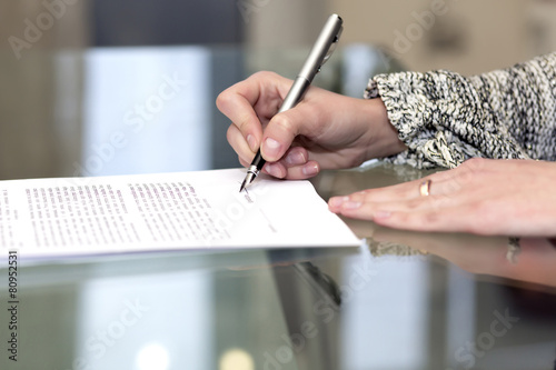 Close up of female hand signing formal paper photo
