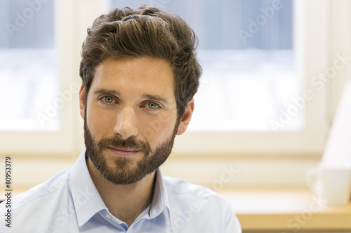 Portrait of handsome bearded man in office. looking at camera