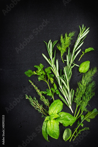 Fresh aromatic herbs with water drops on a black background , to