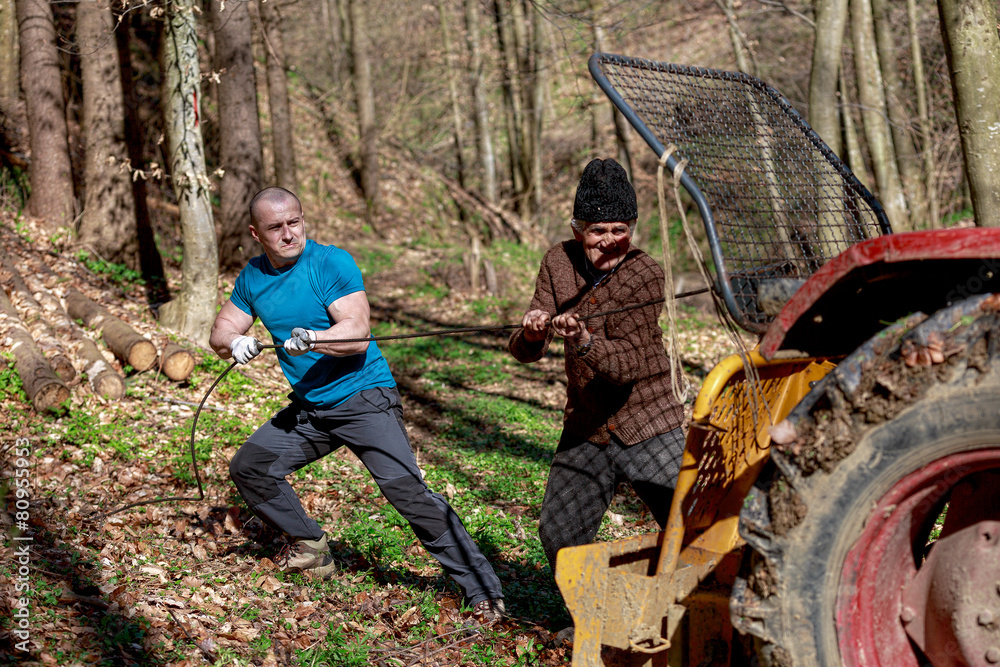 Obraz premium old man and a strong man working with a tractor