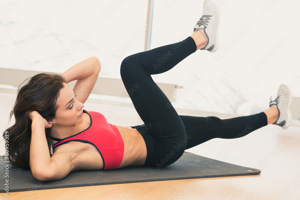 Young woman doing abs workout in a gym on a mat. Young woman doing abs workout in a gym on a mat.