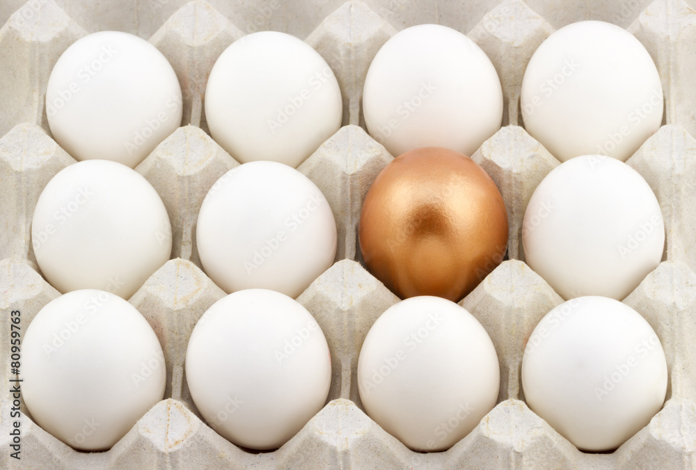 Golden egg arranged in the middle of white eggs in the carton Golden egg arranged in the middle of white eggs in the carton