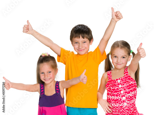 Three cheerful children hold their thumbs up