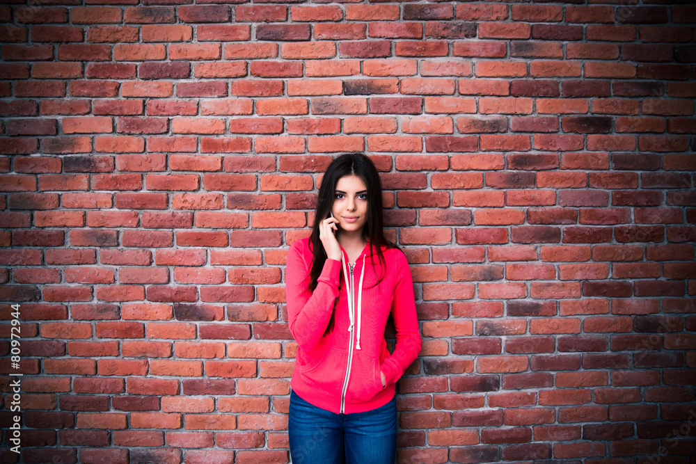 Beautiful woman talking on the phone over brick wall