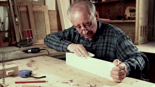 Senior carpenter sending piece of timber with sandpaper photo