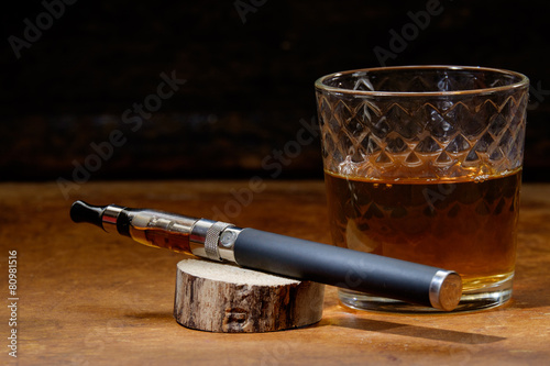 vintage still life with e-cigarette and a glass of bourbon