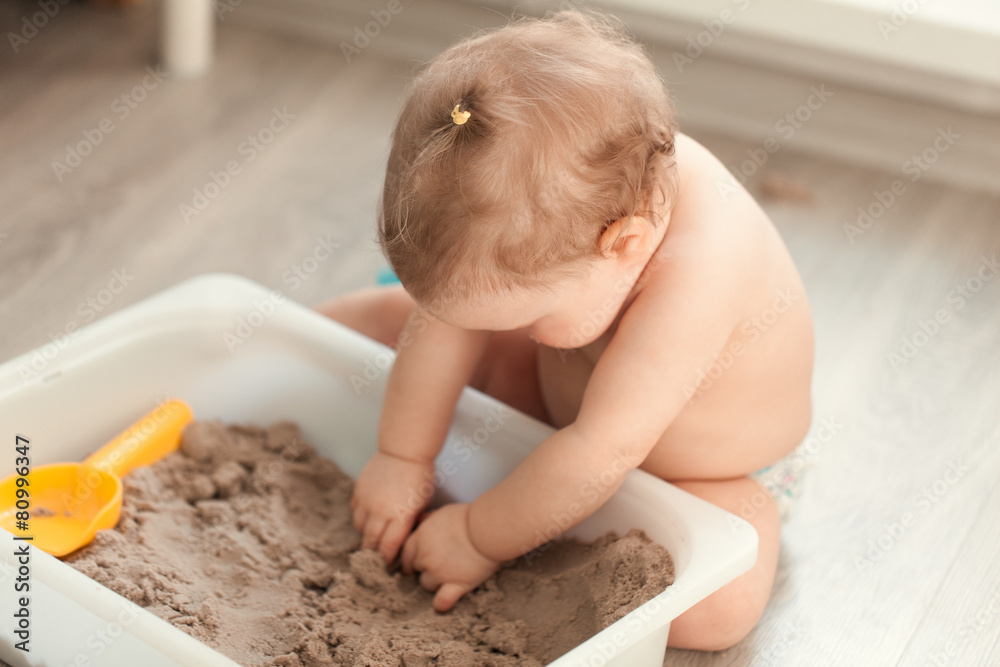 Little girl playing with sand on floor Little girl playing with sand on floor