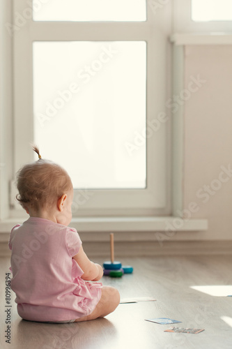 Little girl playing with pyramid on floor photo