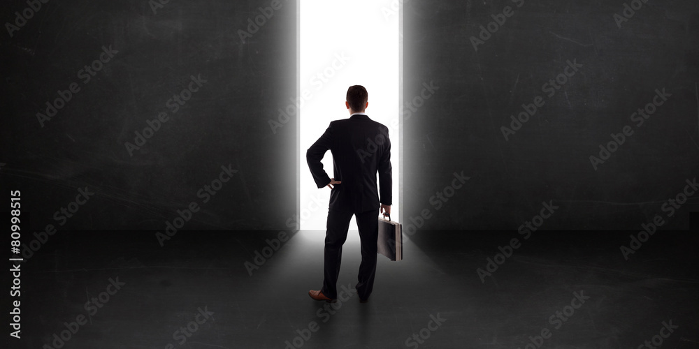 Business person looking at wall with light tunnel opening