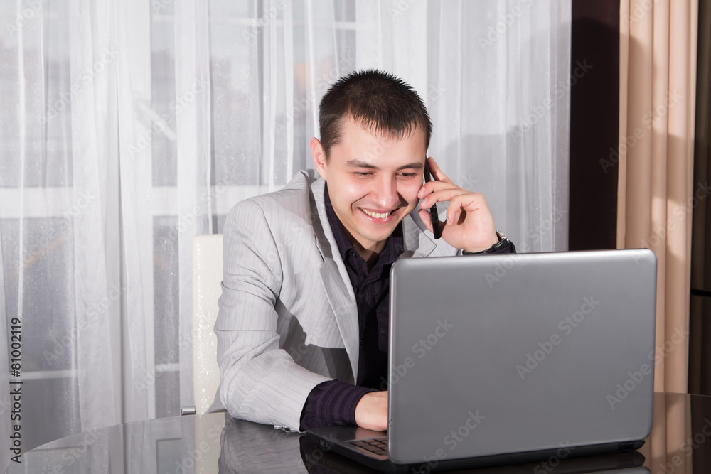 Businessman using a laptop and speaks on mobile phone Businessman using a laptop and speaks on mobile phone