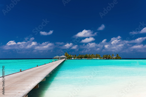 Fototapeta Naklejka Na Ścianę i Meble -  Wooden jetty to a tropical island over lagoon in Maldives
