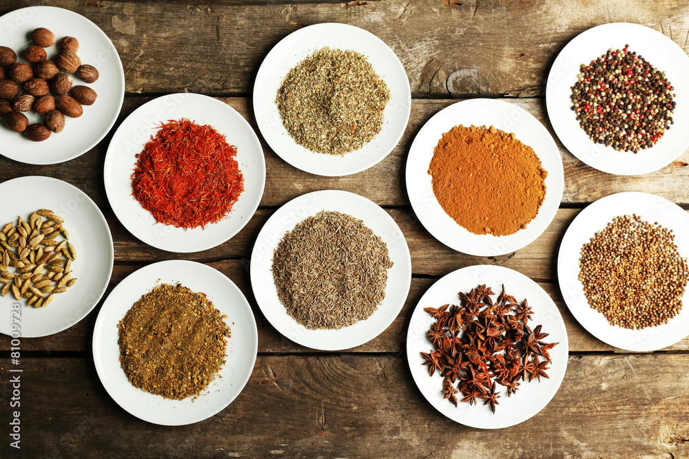 Different spices on plates, on old wooden table