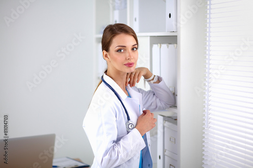 Woman doctor is standing near window