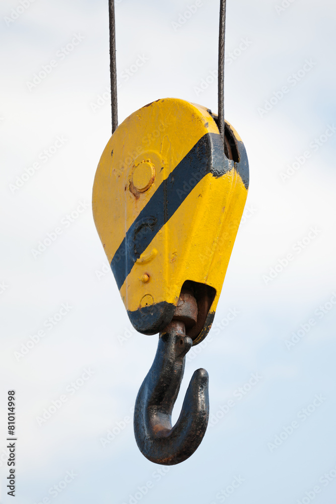Crane hook hanging on steel ropes over cloudy sky Crane hook hanging on steel ropes over cloudy sky
