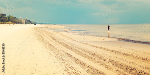 Empty Jurmala beach with lonely girl figure - retro filter.