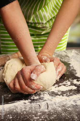 Making dough by female hands on wooden table and blurred background