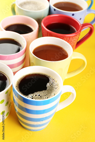 Many cups of coffee on color table, closeup