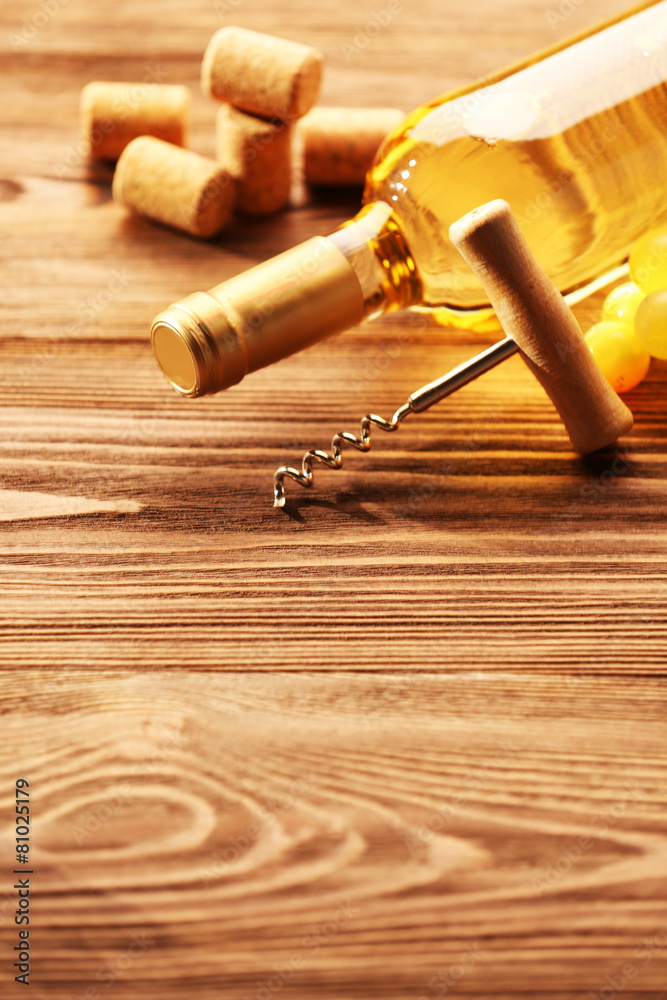 Glass bottle of wine with corks, corkscrew and grapes