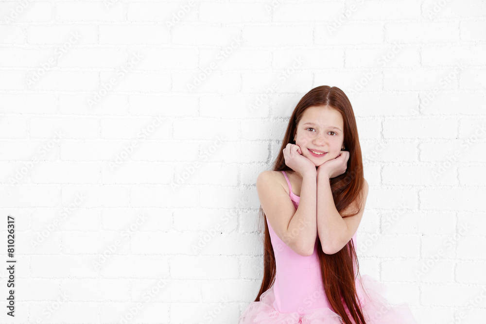 Beautiful little ballerina on white bricks wall background Beautiful little ballerina on white bricks wall background