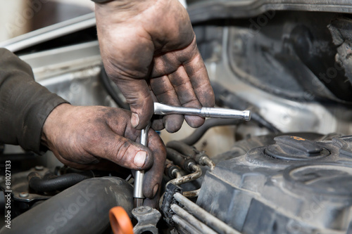 Mechanic with socket wrench repairing car in auto service center