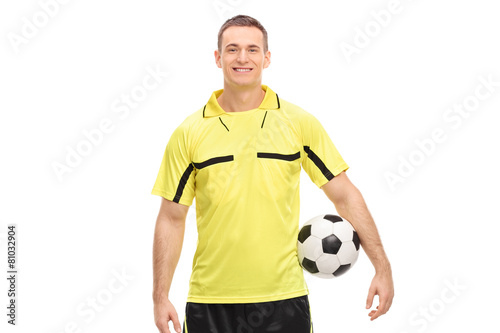 Male football referee in a yellow jersey holding a ball