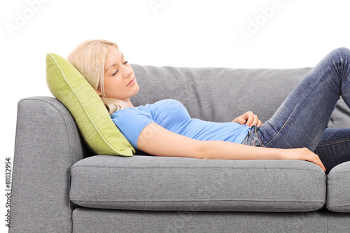 Studio shot of a young blond woman taking a nap on a grey sofa