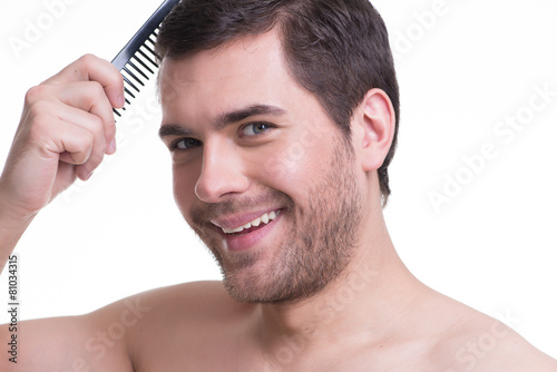 Happy young man combing hair.
