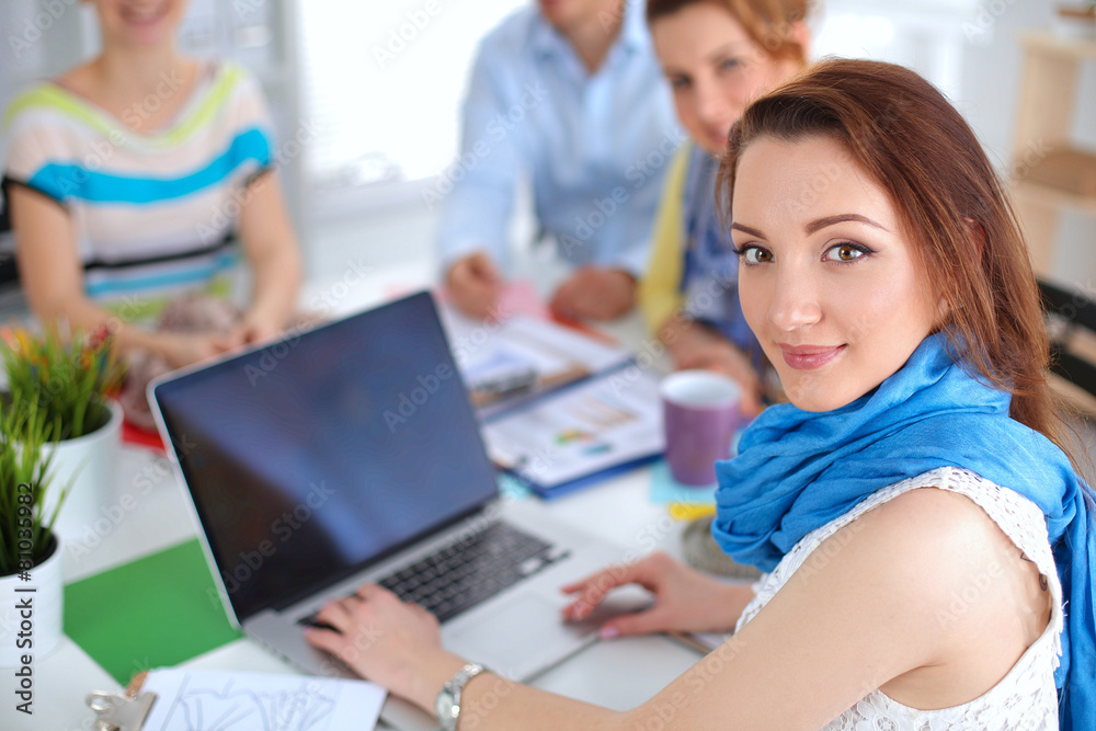Portrait of attractive female designer sittin on thesk in Portrait of attractive female designer sittin on thesk in