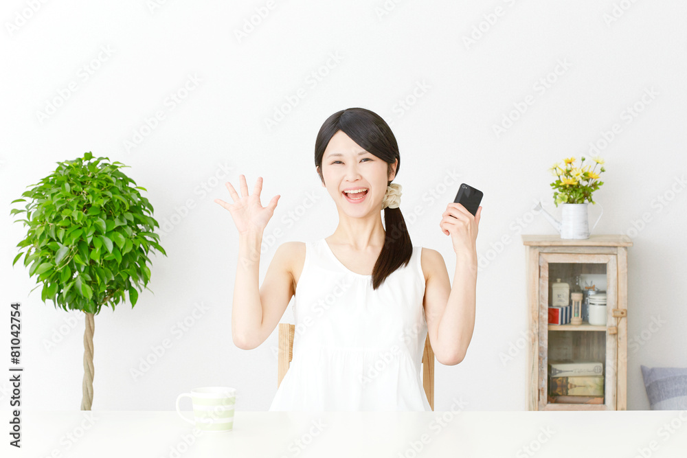 スマートフォンを持って驚く女性