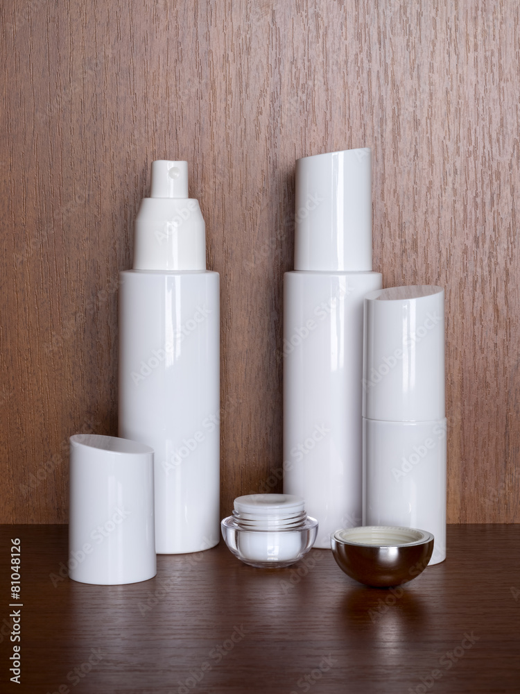 Several white bottles with cosmetic on a wooden table