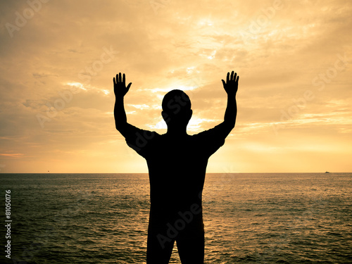 Silhouette man show two hands up in the air at sunset beach