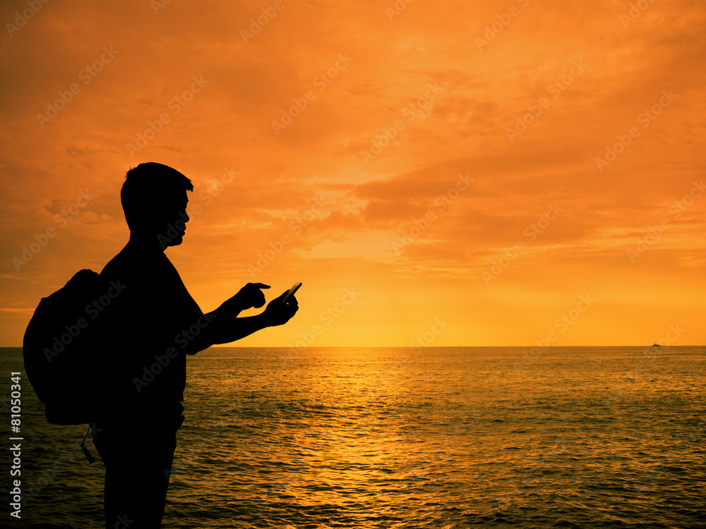 Silhouette man with smartphone in hands at sunset beach